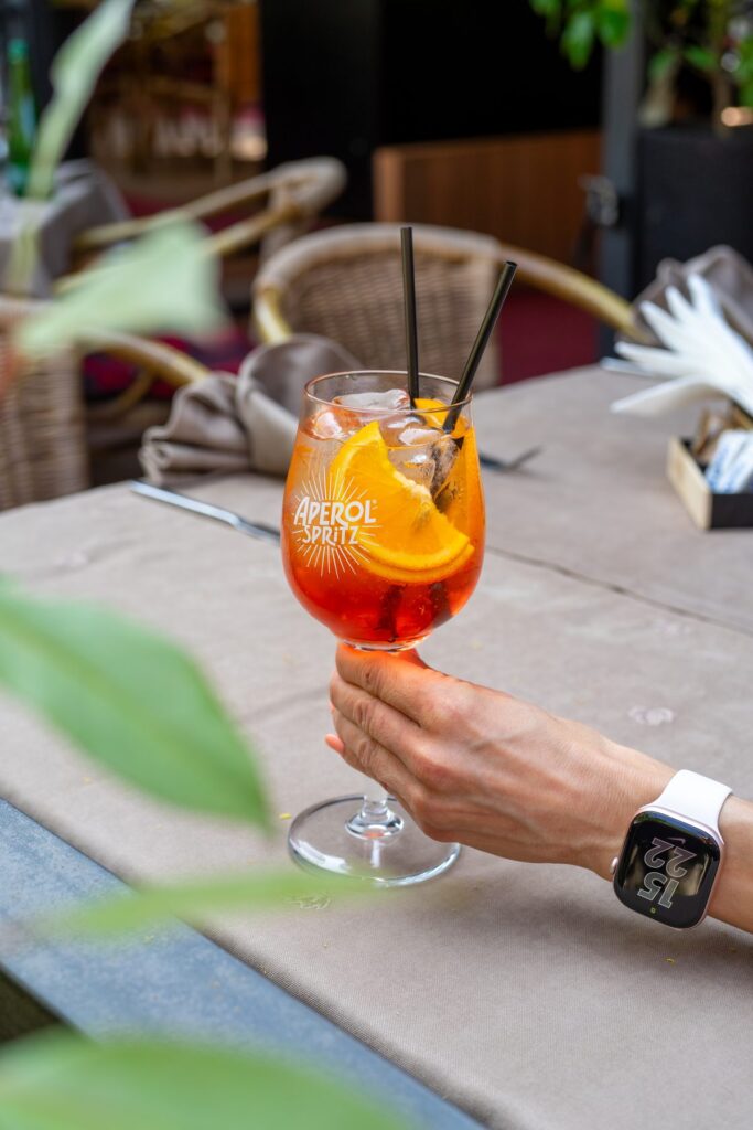 Aperol spritz in a guest's hand on the terrace