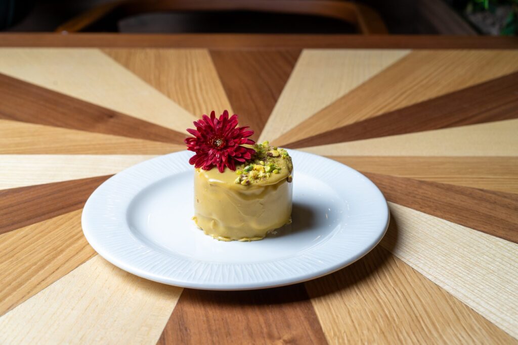 Pistachio dessert with a red flower on a white plate