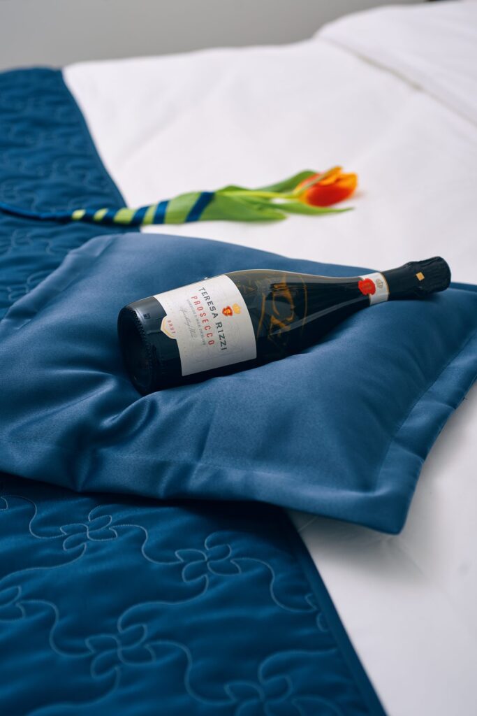 Welcome in a hotel room - a bottle and a tulip on the bed