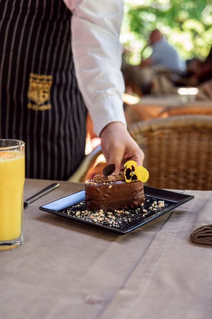 Waiter serving a chocolate cake with an edible flower